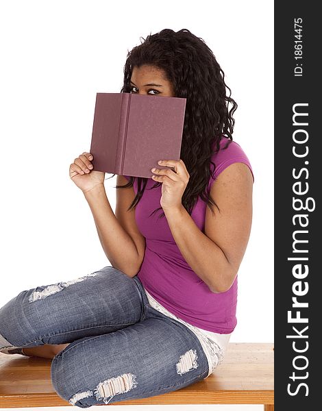 An African American woman is peaking over a book. An African American woman is peaking over a book.