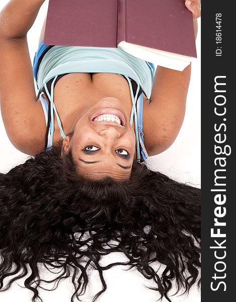 An African American woman is laying upside down with a book and a smile. An African American woman is laying upside down with a book and a smile.