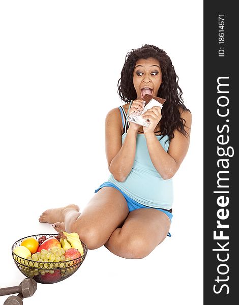 Woman eating chocolate looking at fruit