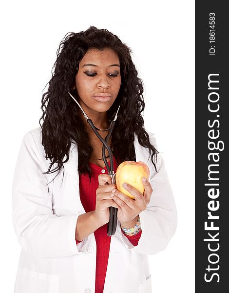 A Woman with a stethoscope is looking down at an apple. A Woman with a stethoscope is looking down at an apple.