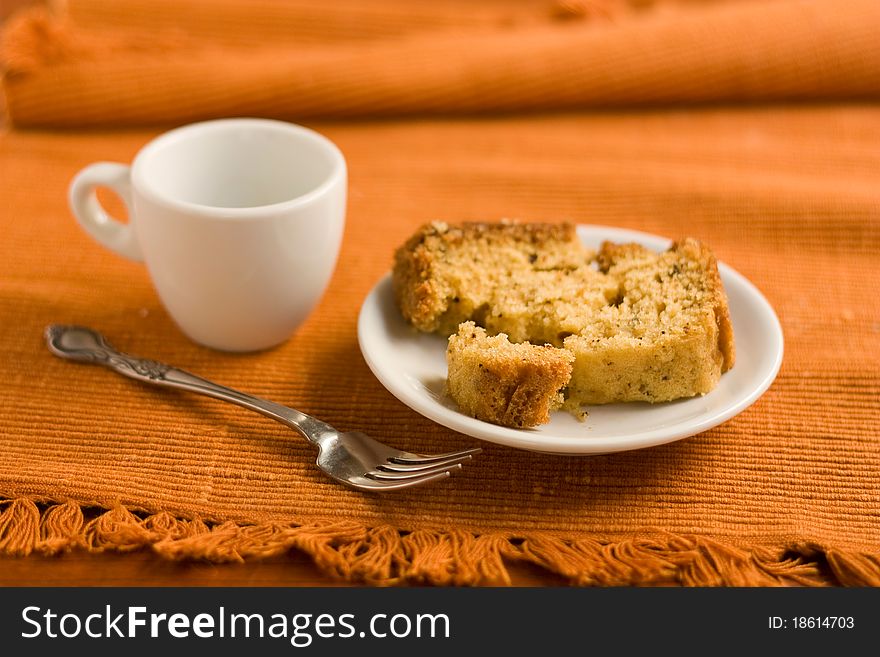 Broken cake on a plate, fork and a cup of coffee on a napkin. Broken cake on a plate, fork and a cup of coffee on a napkin.