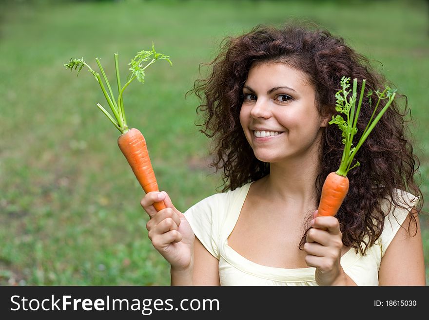 Outdoor portrait of smiling woman with fresh carrots. Outdoor portrait of smiling woman with fresh carrots.