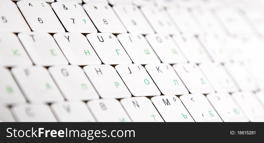 Close-up view at laptop keyboard with english and russian letters.