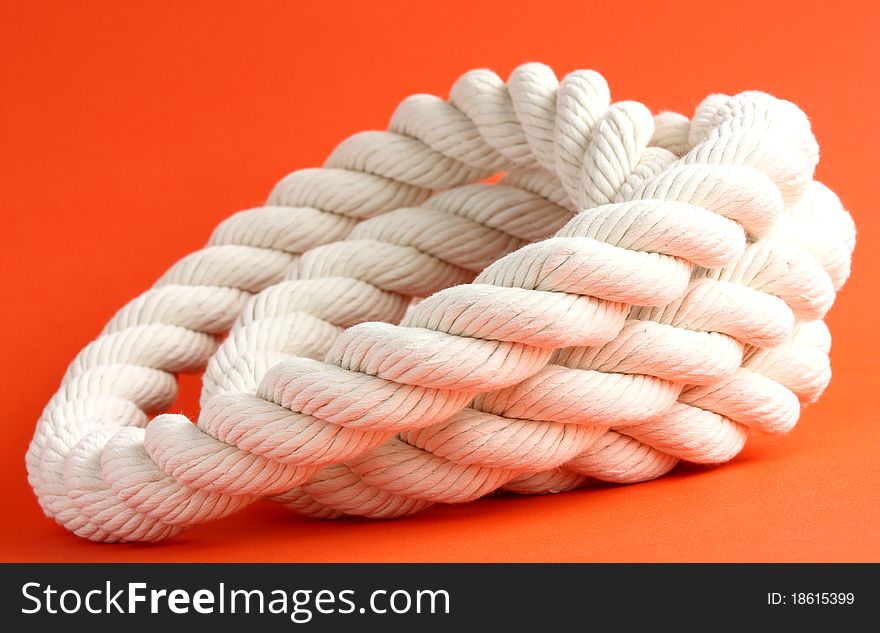 Close-up of a twisted white cable on red background