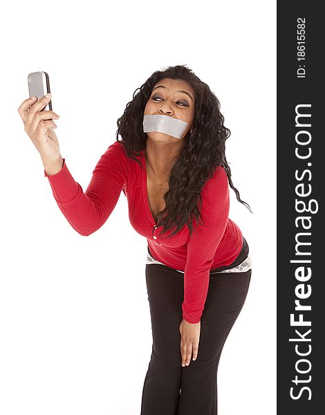 An African American woman has a phone and is taking a picture with her mouth taped shut. An African American woman has a phone and is taking a picture with her mouth taped shut.