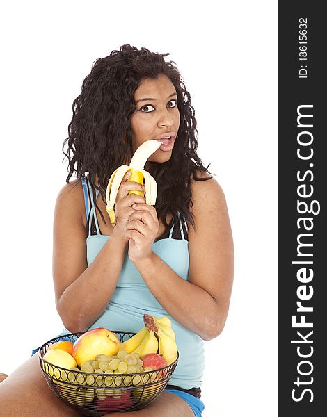 An African American woman is biting a banana. An African American woman is biting a banana.