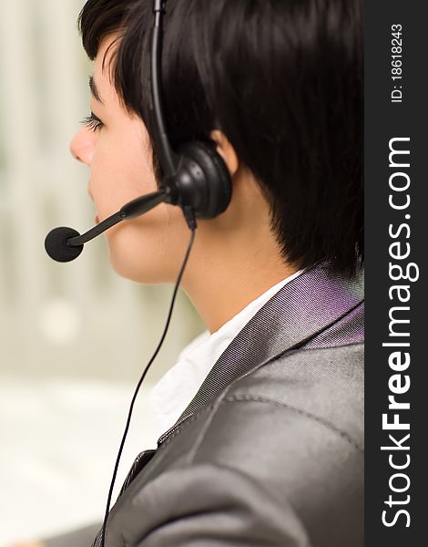 Profile of an Attractive Young Mixed Race Woman Smiles Wearing Headset In An Office Setting. Profile of an Attractive Young Mixed Race Woman Smiles Wearing Headset In An Office Setting.