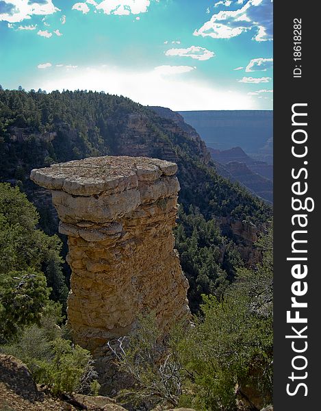 Singular standing rock formation between the arid vegetation of the grand canyon