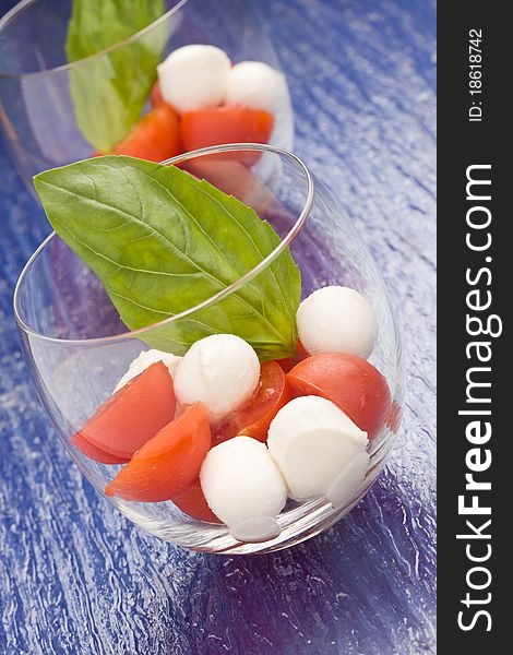 Photo of italian caprese salad made of tomatoe and mozarella in glass with basil leaf. Photo of italian caprese salad made of tomatoe and mozarella in glass with basil leaf