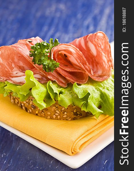 Delicious salami and lettuce sandwich on yellow cloth with parsley. Delicious salami and lettuce sandwich on yellow cloth with parsley