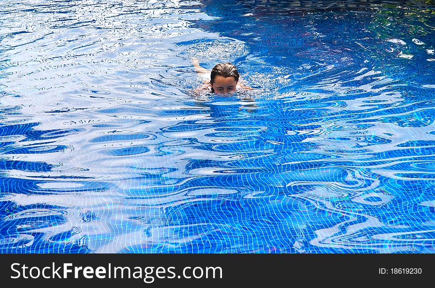 A preteen girl swimming in a pool above water. A preteen girl swimming in a pool above water.