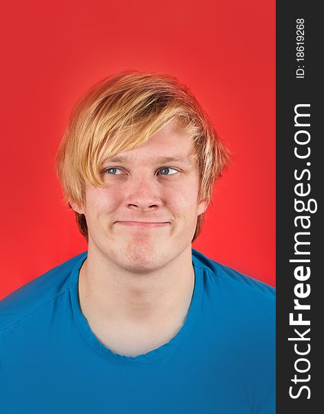 Displeased young man showing no emotions on red background