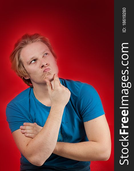 Young man with thoughtful pose on red background. Young man with thoughtful pose on red background