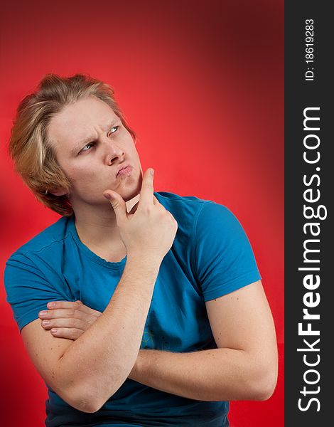 Young man with thoughtful pose on red background. Young man with thoughtful pose on red background