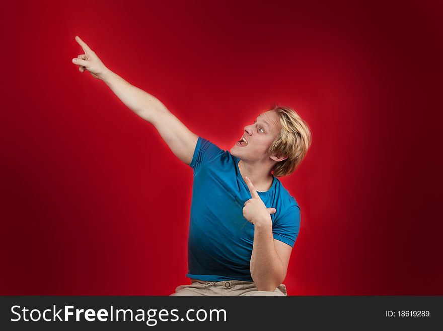 Man pointing on red copy-space with wild facial expression. Man pointing on red copy-space with wild facial expression