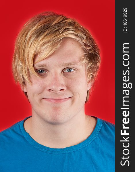 Displeased young man showing no emotions on red background. Displeased young man showing no emotions on red background