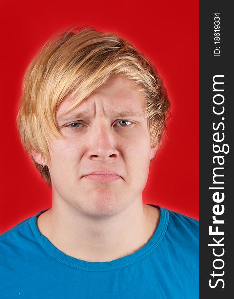 Displeased young man showing no emotions on red background. Displeased young man showing no emotions on red background