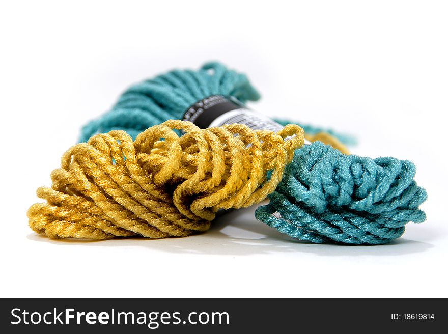 Two overlapping skeins of yellow and blue yarn on a white background