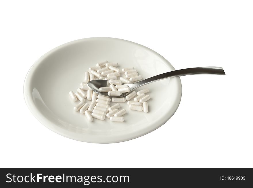 White plate with pills and spoon isolated