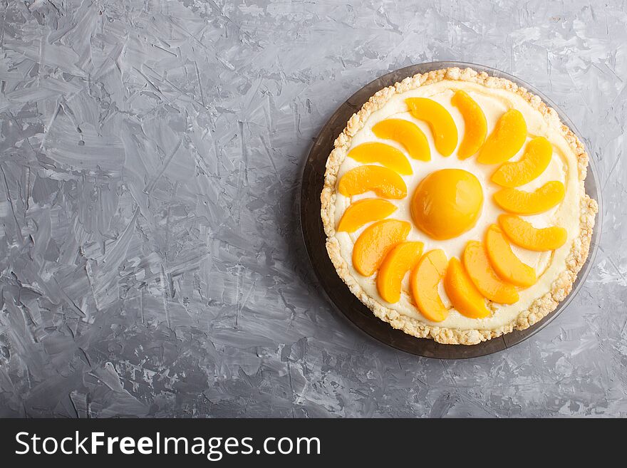 Round peach cheesecake on a gray concrete background. top view, flat lay, copy space. Round peach cheesecake on a gray concrete background. top view, flat lay, copy space