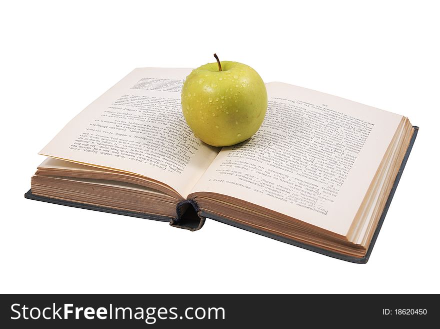 He old opened book with a fresh apple lying from above. He old opened book with a fresh apple lying from above