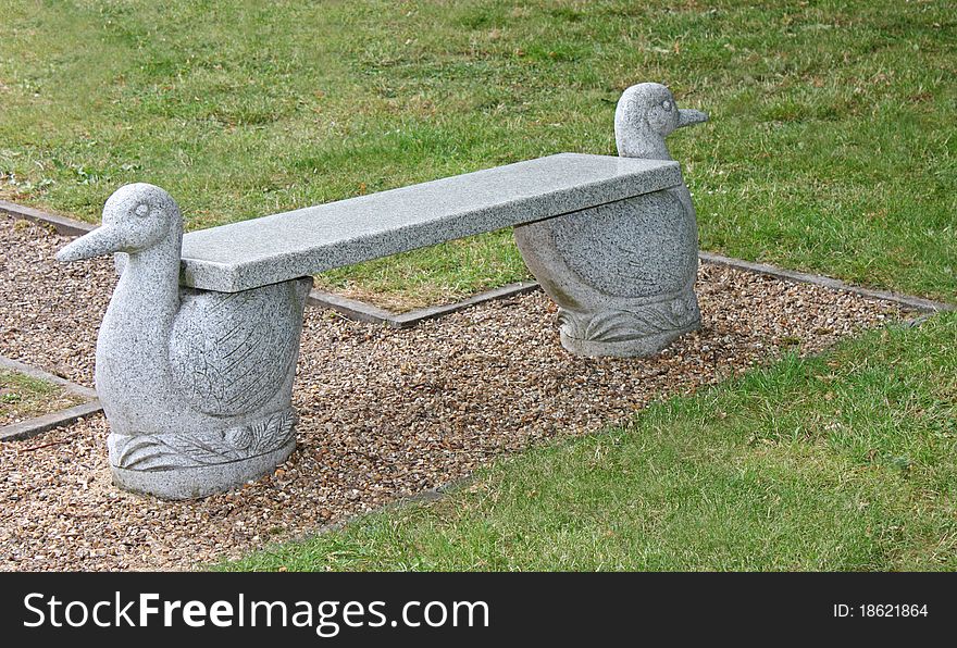An Outdoors Stone Bench with Bird Design Supports.