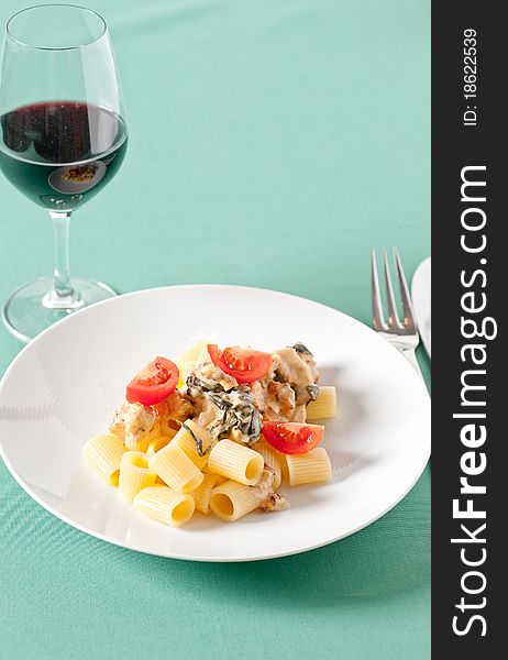 Chicken with pasta and fresh cherry tomatoes on a pastel tablecloth