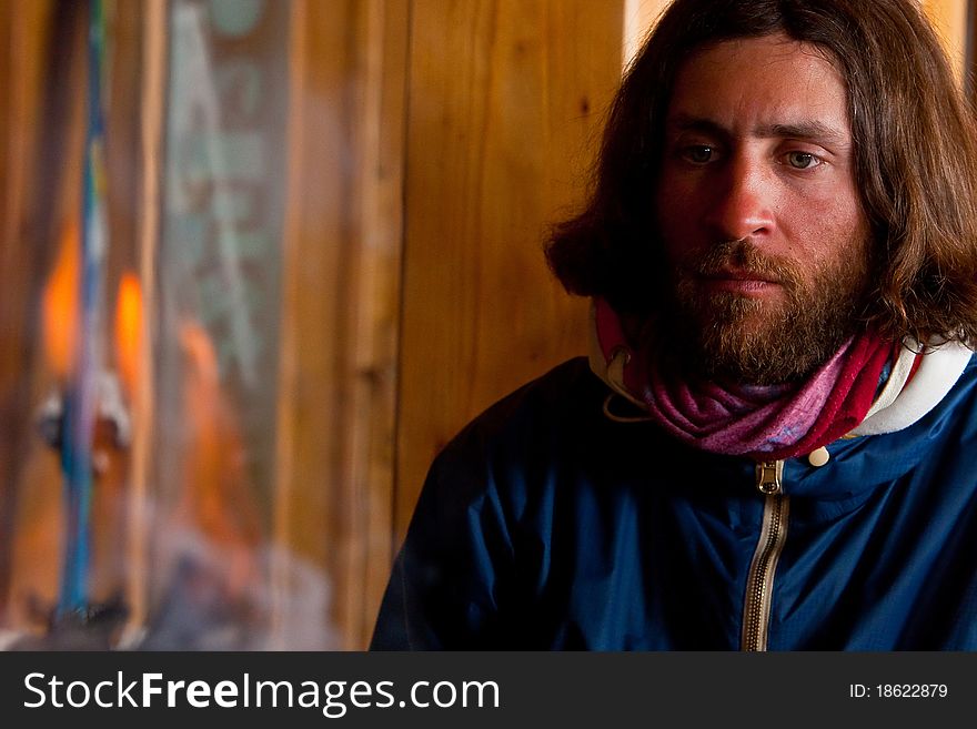 A man with long hair near a fire. A man with long hair near a fire