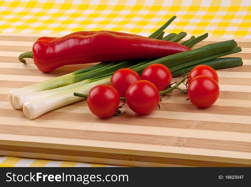 Green onion, tomatoes and red pepper on a wooden tray