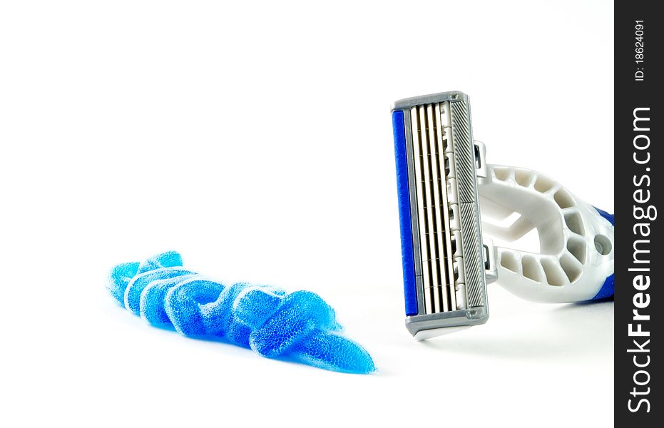 Closeup of blue shaving blade with foam on white surface