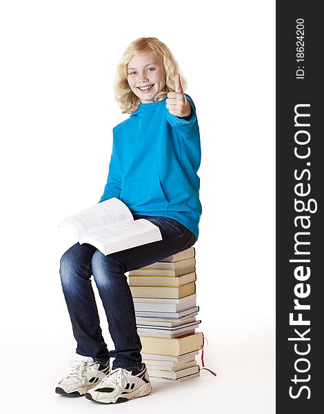 Happy schoolgirl sitting on school books showing thumb up. Isolated on white background. Happy schoolgirl sitting on school books showing thumb up. Isolated on white background.