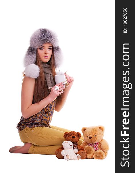 Beautiful brunette in a fur hat sitting next to a few teddy bears