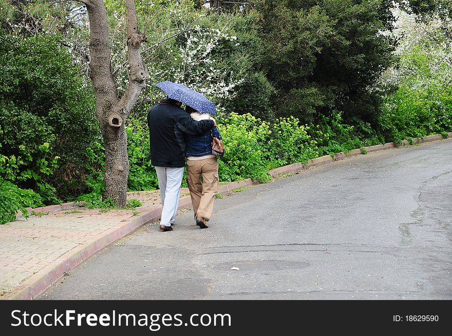 A couple walking under umbrella during rain. A couple walking under umbrella during rain