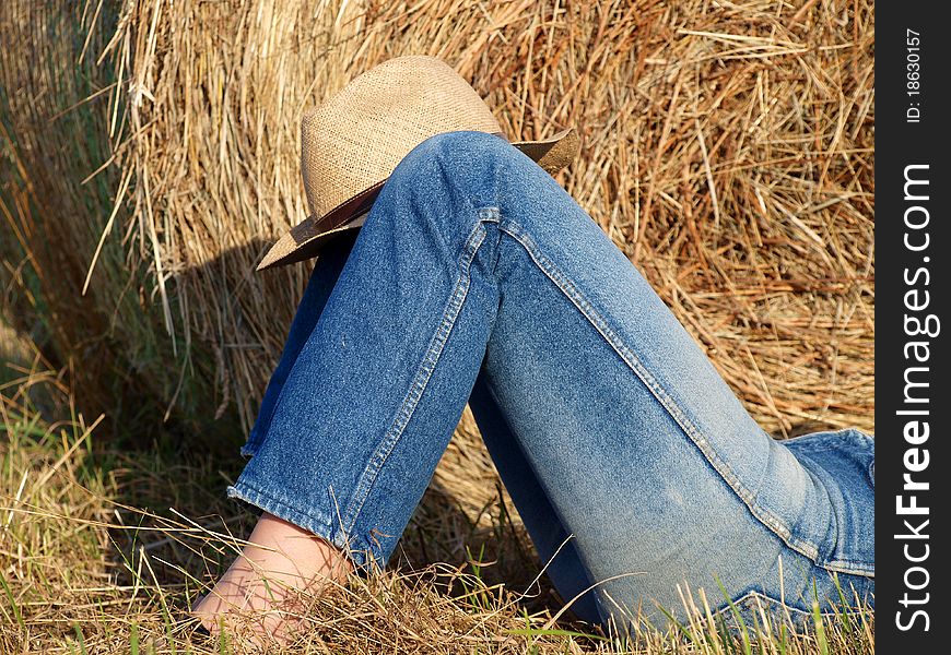 Woman legs in jeans in front of a straw bale. Woman legs in jeans in front of a straw bale