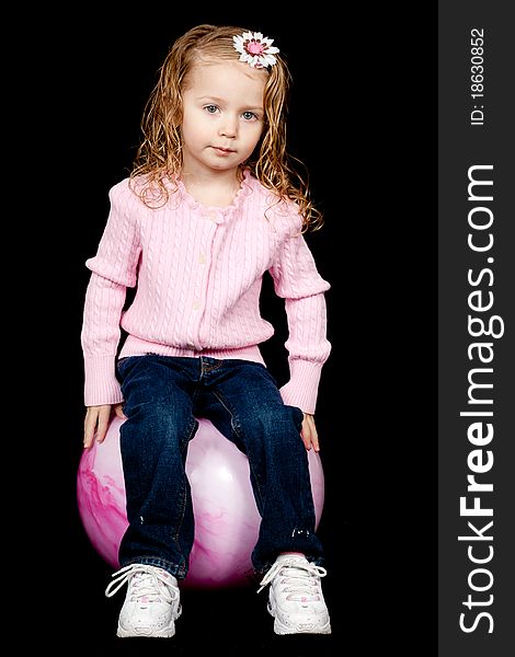 A lone content child sitting on her pink rubber ball. A lone content child sitting on her pink rubber ball.