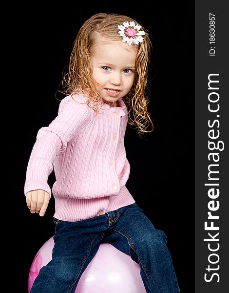 An adorable young child playing on a pink ball. An adorable young child playing on a pink ball.