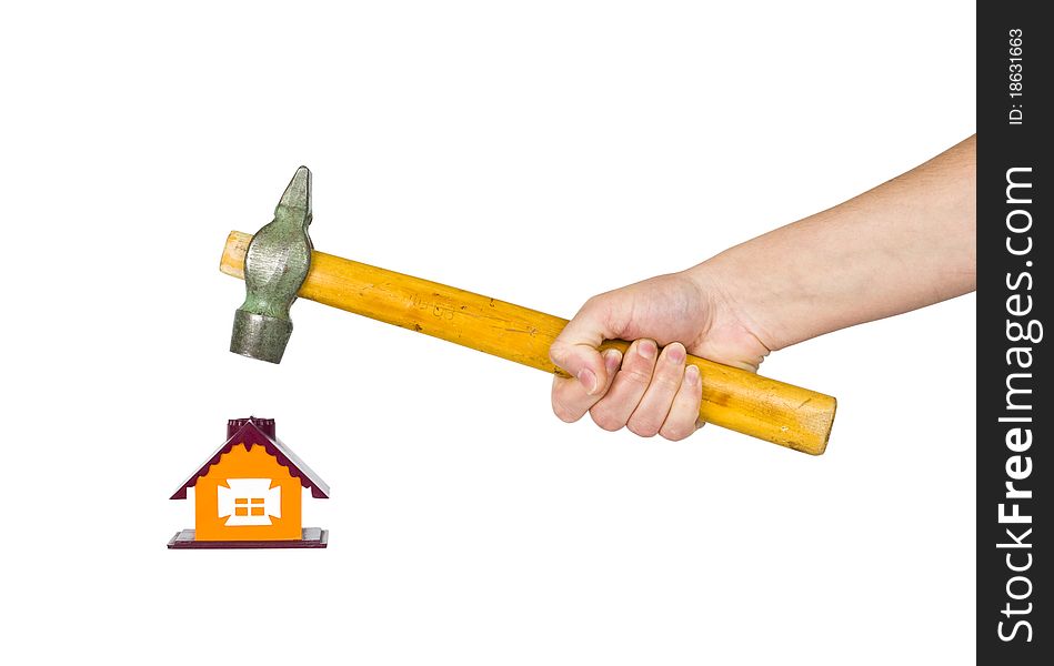 Hand with a hammer destroys small house. Hand with a hammer destroys small house