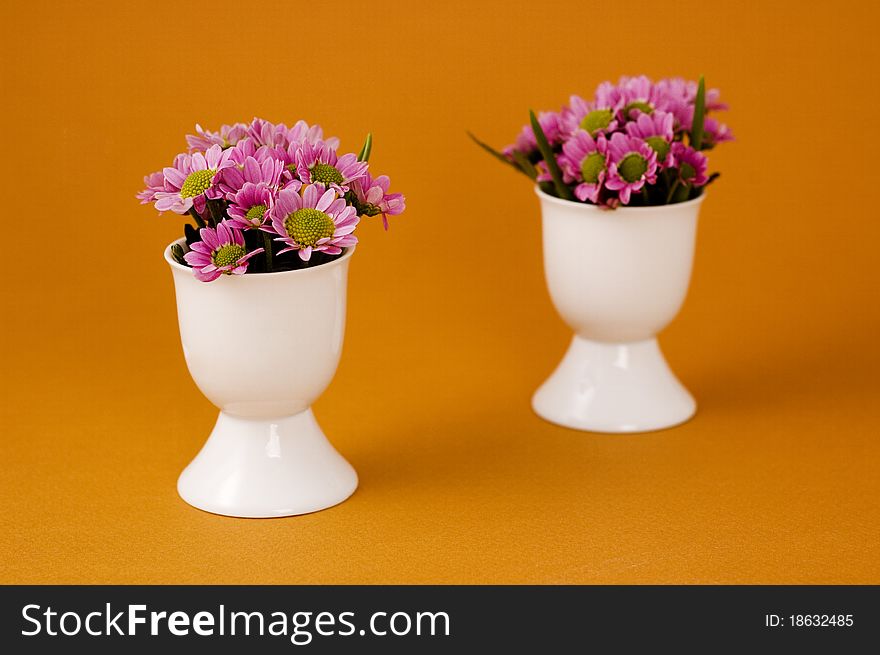 Pink chrysanthemum in an egg cups on light brown background