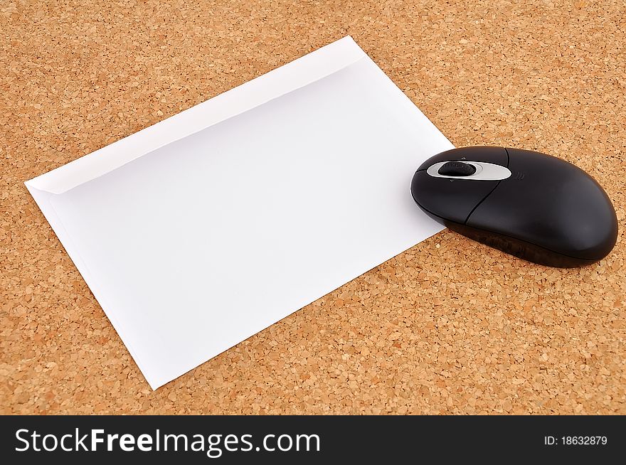 Wireless mouse and an envelope on the cork background