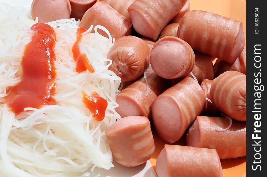 Dish with sausage, noodles and red sauce closeup.