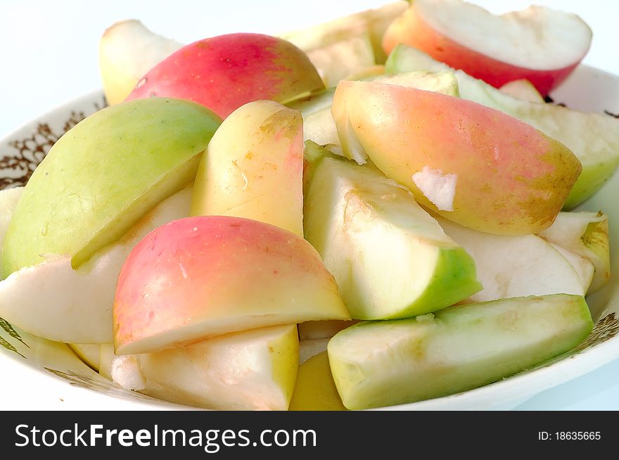 Multi-colored pieces of sliced apples on a plate closeup.