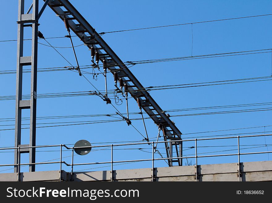 Railway gantry with high voltage cables and insulators suspended beneath.