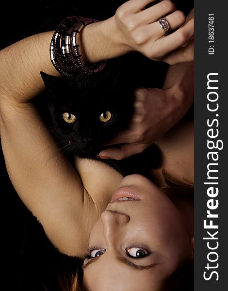 View of a beautiful woman on the bed with a black cat. View of a beautiful woman on the bed with a black cat.