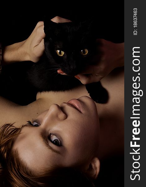 View of a beautiful woman on the bed with a black cat. View of a beautiful woman on the bed with a black cat.