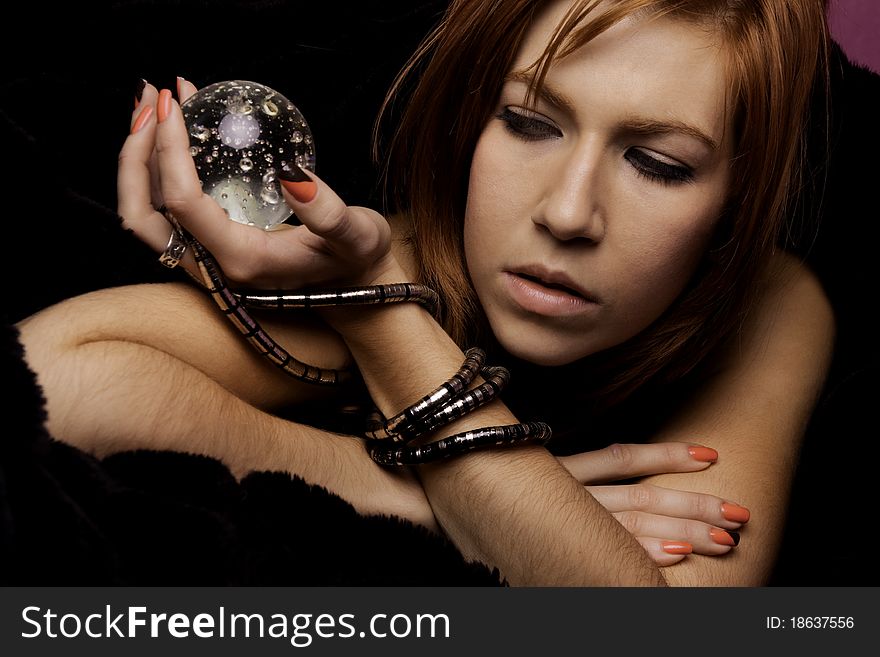 View of a beautiful woman on the bed with a transparent glass ball. View of a beautiful woman on the bed with a transparent glass ball.