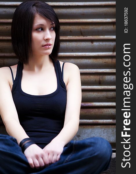 Young beautiful girl sitting on urban background. Young beautiful girl sitting on urban background