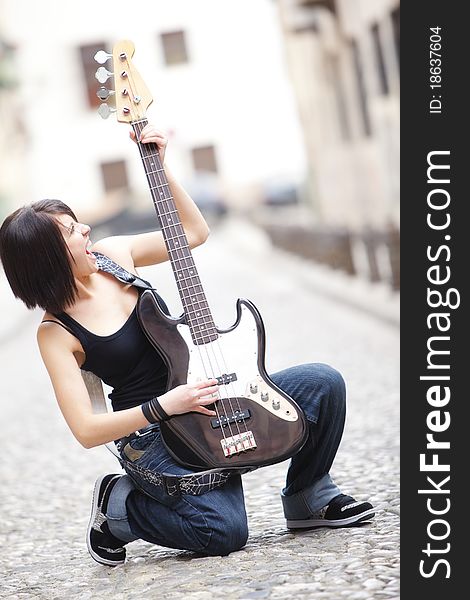 Joyful young woman playing a guitar at the street. Joyful young woman playing a guitar at the street