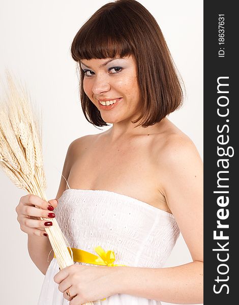 Beautiful brunette girl with ears of wheat in her hair isolated on the white background