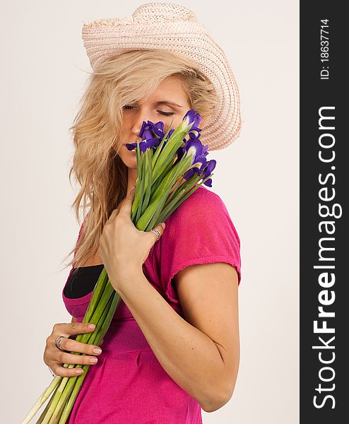 Beautiful girl with blonde hair holding a bouquet of irises. She is in studio isolated on a white background. Beautiful girl with blonde hair holding a bouquet of irises. She is in studio isolated on a white background