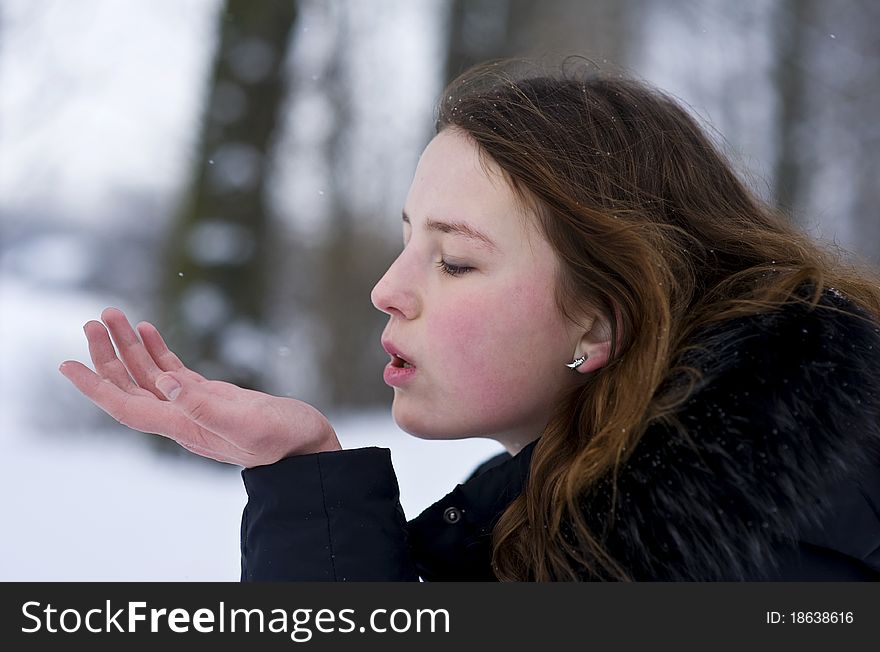 Beautiful young girl blowing kiss in winter day